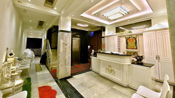 Un hall d’hôtel comprenant un comptoir d’accueil, un espace salon et un escalier menant aux autres étages.