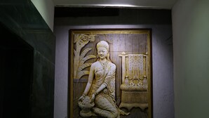 Une sculpture murale représentant une figure assise, avec un décor en arrière-plan.