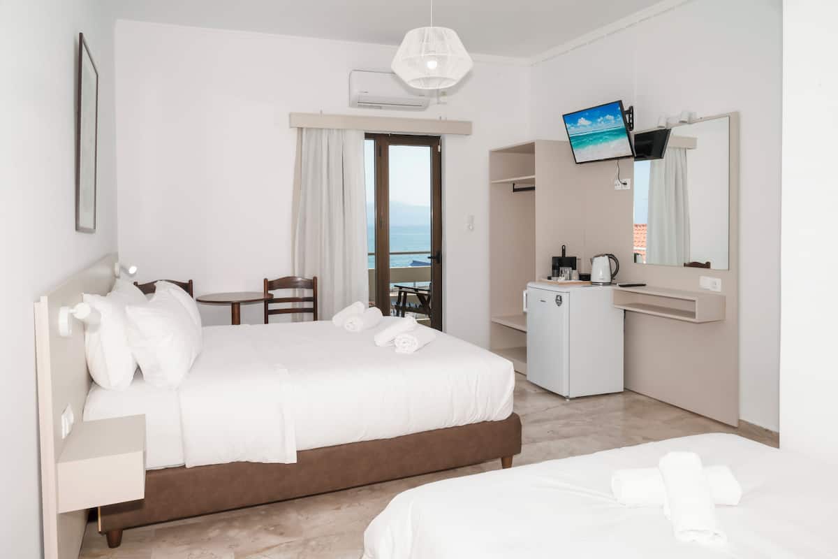 Habitación de hotel con cama, escritorio, televisor y vistas al mar.