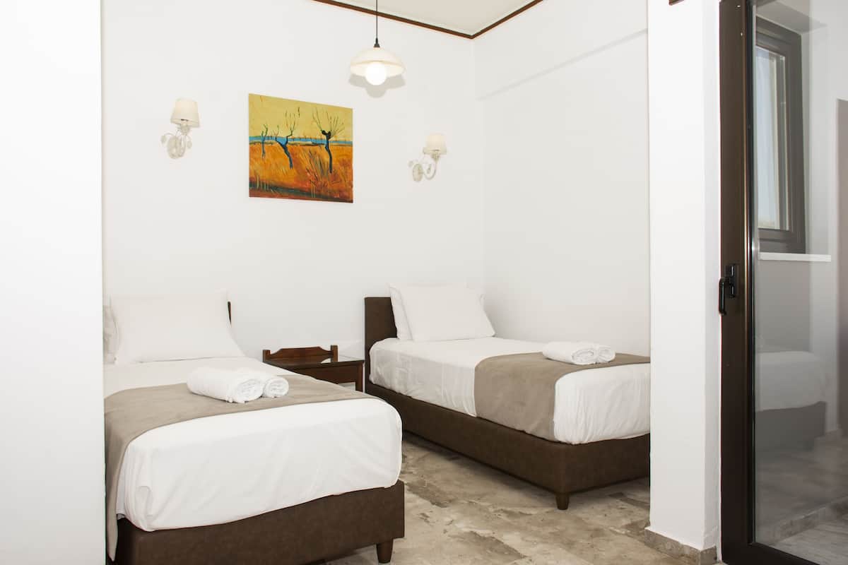 Habitación de hotel con dos camas, un cuadro en la pared y una ventana.