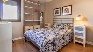 Une chambre à coucher comprenant un lit, des tables de chevet, une armoire et une fenêtre avec un rideau.