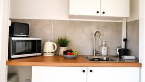 A modern kitchen with a microwave, kettle, sink, and a bowl of fruit. - Lodge 7 - Lytton Tree Lodge, Reydon, Southwold (Reydon)