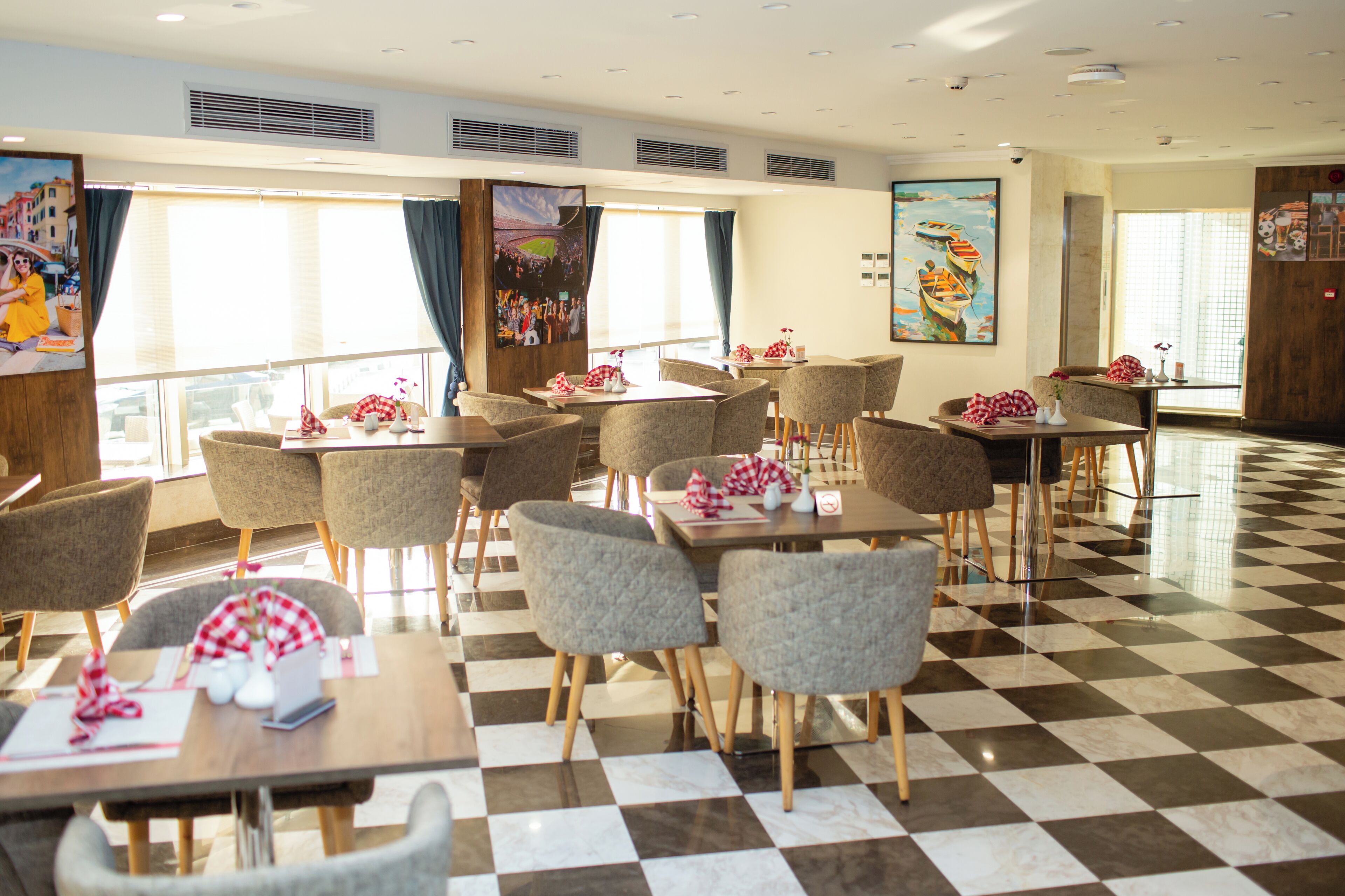 Comedor de hotel con suelo de cuadros, varias mesas y sillas.