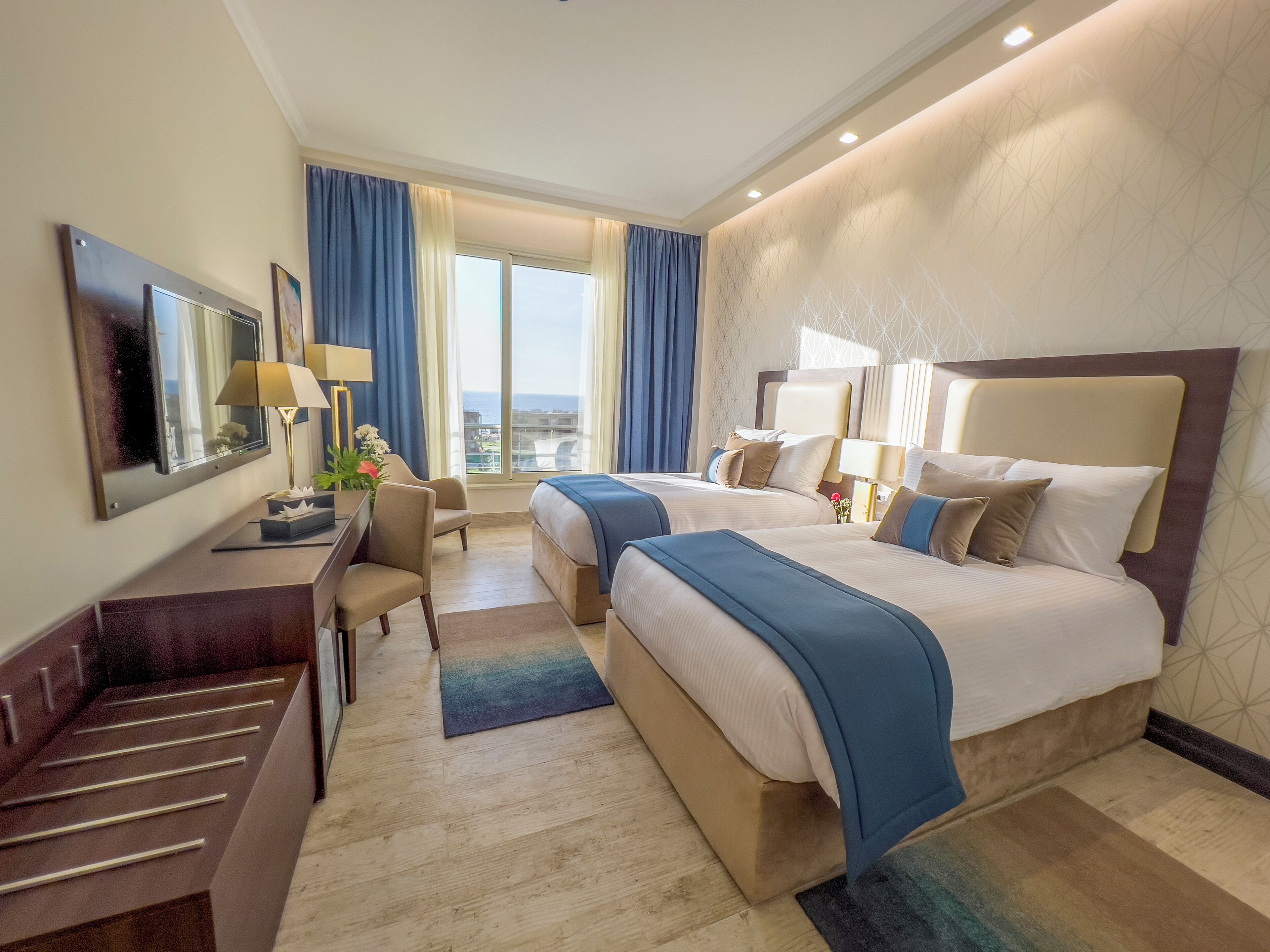 Une chambre d’hôtel avec deux lits, un bureau, une chaise et un téléviseur.