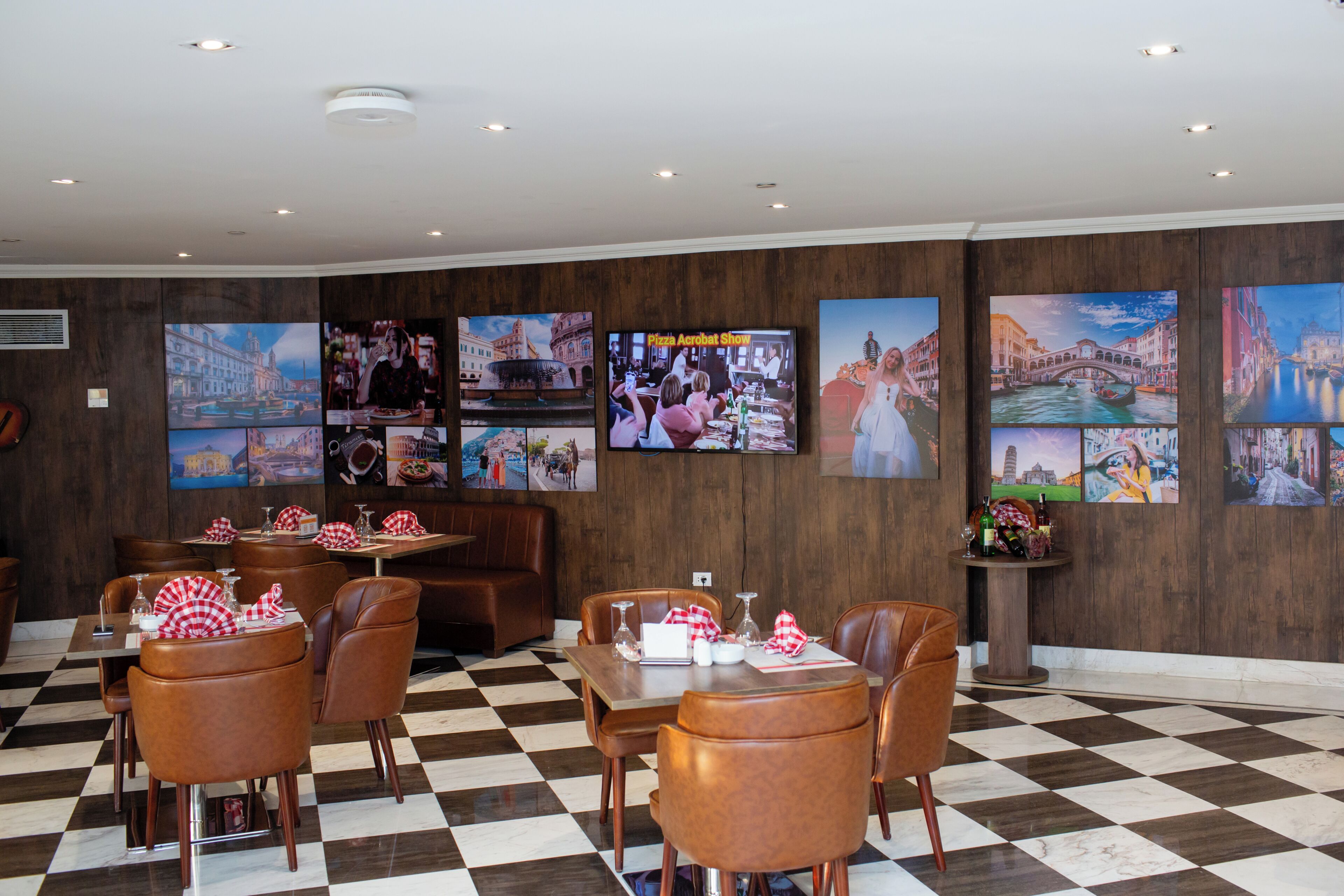 Un restaurante con piso de cuadros, sillas de cuero marrón y una pared decorada con diversas fotografías de paisajes urbanos.