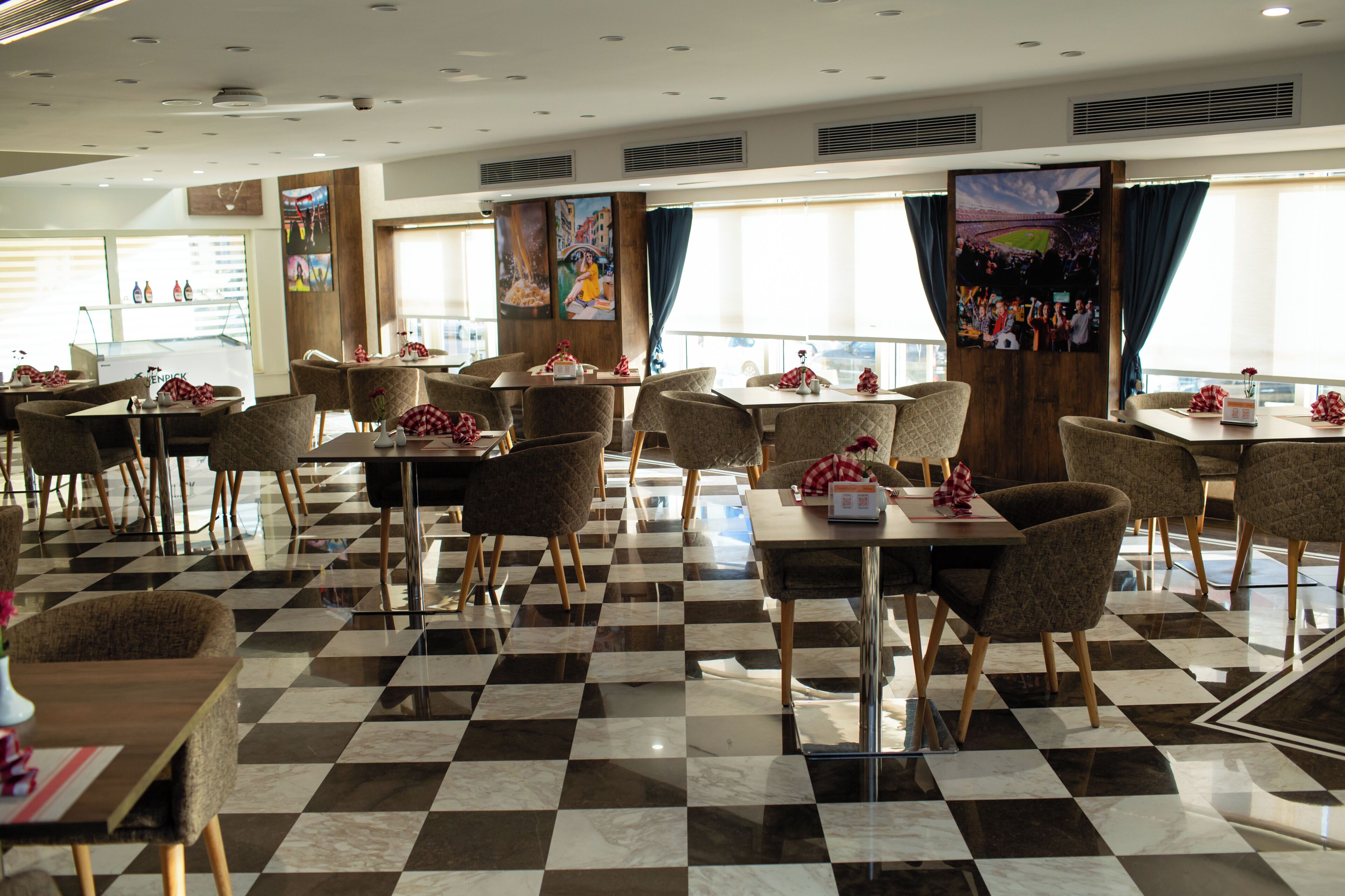 A hotel dining area with checkered flooring, multiple tables, and chairs.