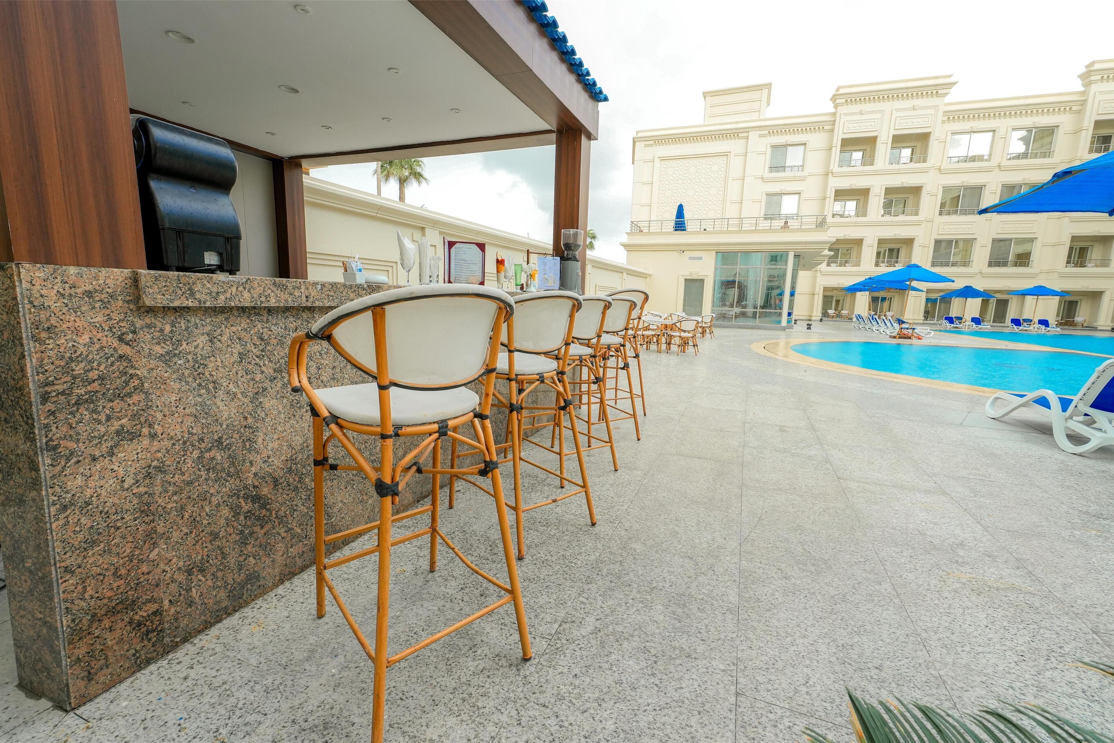 A poolside area with wicker chairs and a pool.