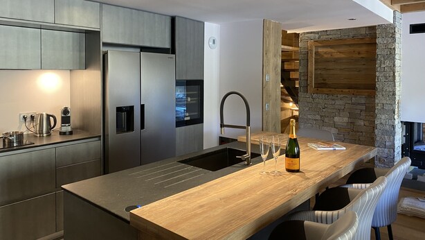 Een moderne keuken met roestvrijstalen apparatuur, een houten kookeiland en een accentmuur van steen.
