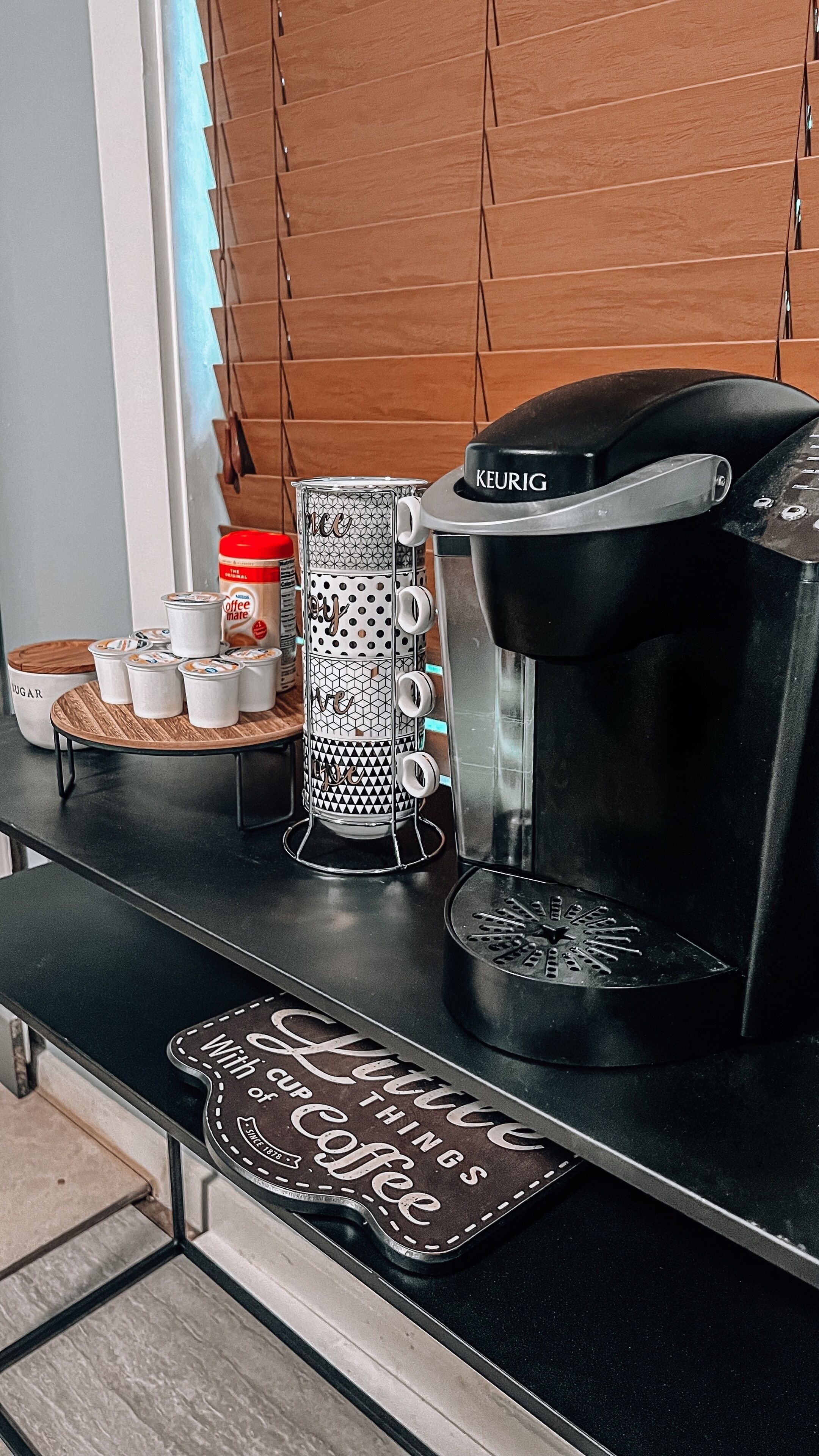 Kaffestation med en Keurig-kaffemaskine, kaffekværn og bakke med kaffekopper og en kaffemugge.