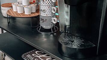 Kaffestation med en Keurig-kaffemaskine, kaffekværn og bakke med kaffekopper og en kaffemugge.
