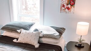 Une chambre à coucher avec un lit, une table de chevet avec une lampe, un tapis et deux tableaux accrochés au mur.