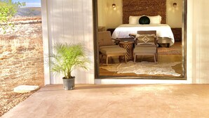 A bedroom with a bed, two chairs, a small table, and a potted plant. - BirdSong Desert Retreat: Reconnect. Rejuvenate. (Nogales)