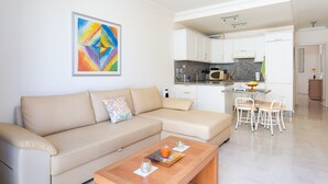 A modern living room with a beige sofa, a wooden coffee table, and a colorful abstract painting on the wall. - Apartment El Faro for 3 people in the south of Tenerife (Palm-Mar)