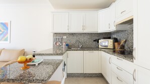 A kitchen with white cabinets, a granite countertop, a microwave, and a fruit bowl. - Apartment El Faro for 3 people in the south of Tenerife (Palm-Mar)