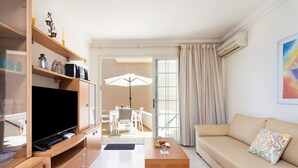 A modern living room with a flat-screen TV, wooden shelving, a beige sofa, and a dining area with a table and chairs. - Apartment El Faro for 3 people in the south of Tenerife (Palm-Mar)