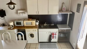 Una cocina compacta con electrodomésticos básicos, lavadora y un lavamanos pequeño.