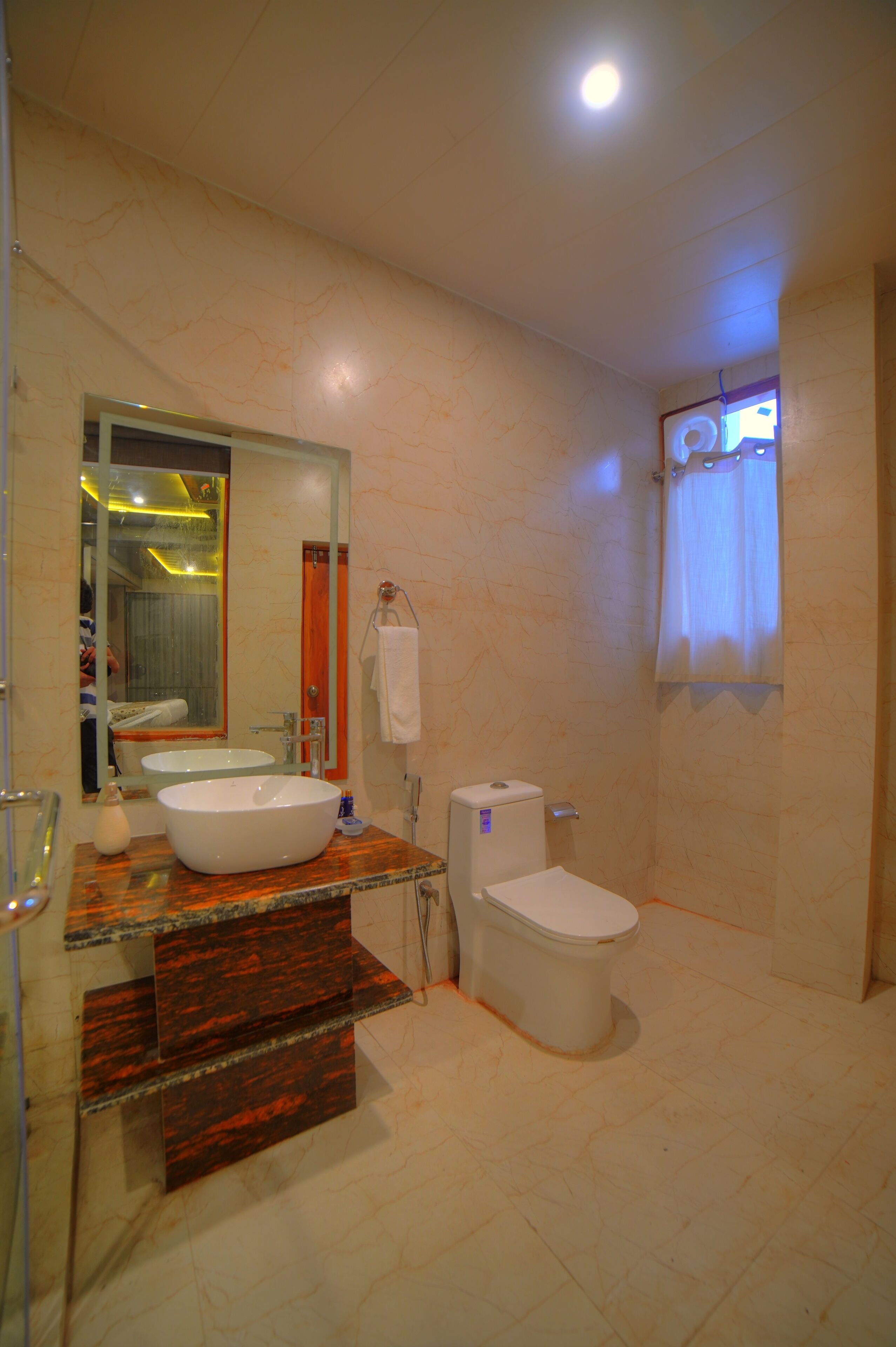 A bathroom with a marble vanity, a large mirror, a toilet, and a shower area.