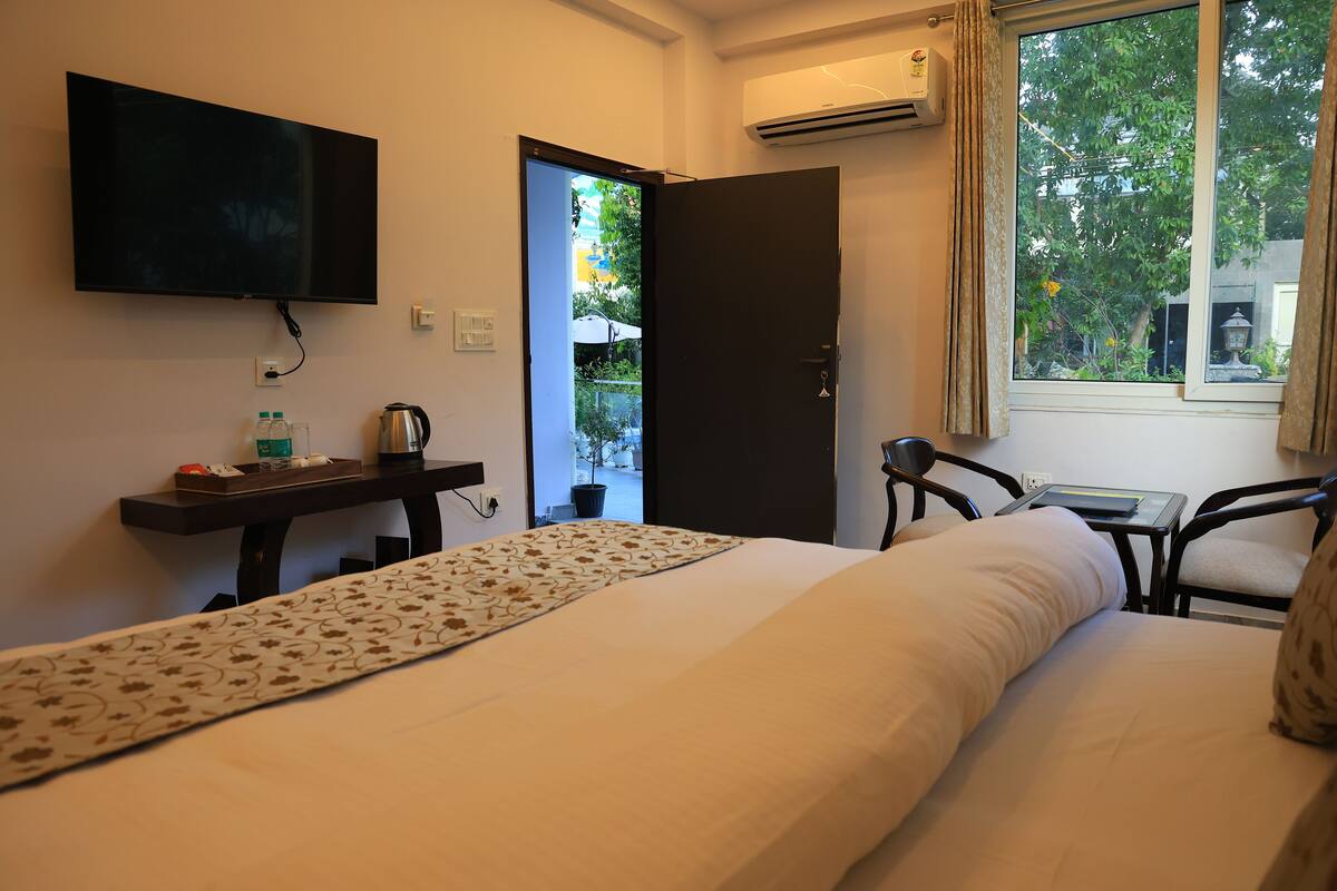 A hotel room with a bed, a desk, a chair, a television, and a window with a view of the outdoors.