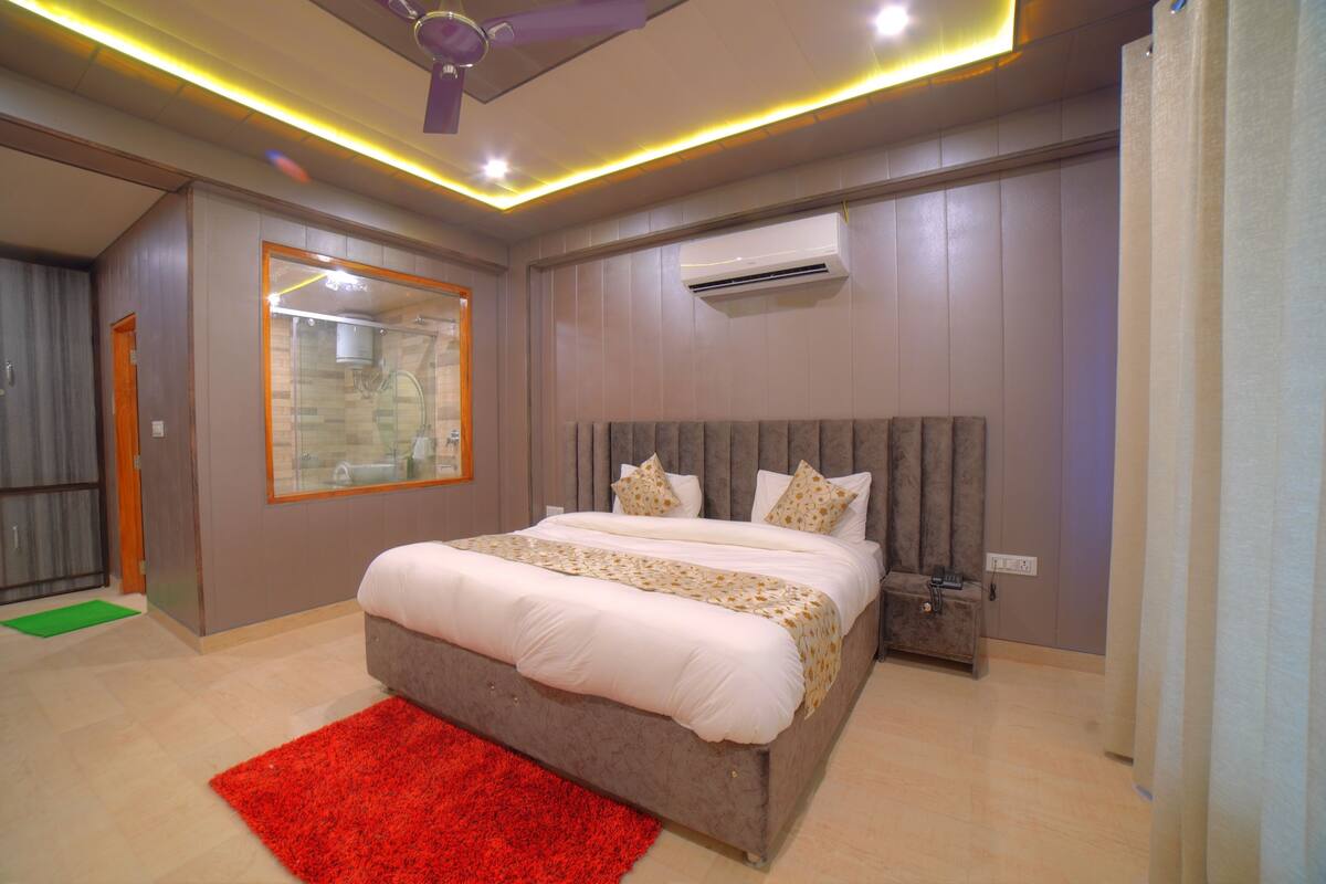 A modern bedroom with a large bed, a red rug, and an air conditioning unit on the wall.