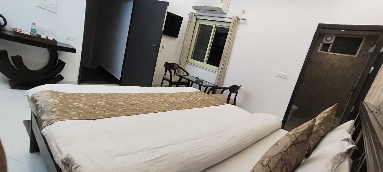A bedroom with a bed, a desk, a chair, a window, and a door.
