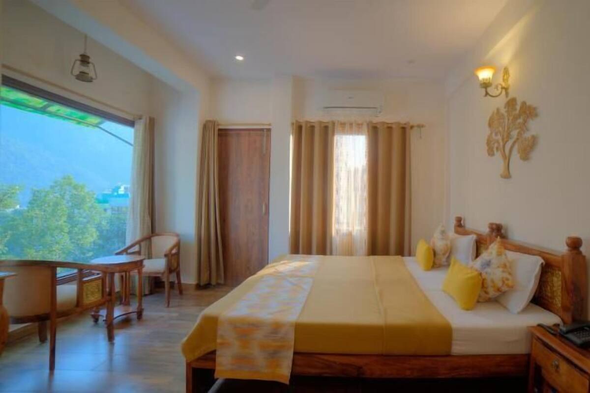A bedroom with a bed, bedside table, chair, and a view of the outdoors.