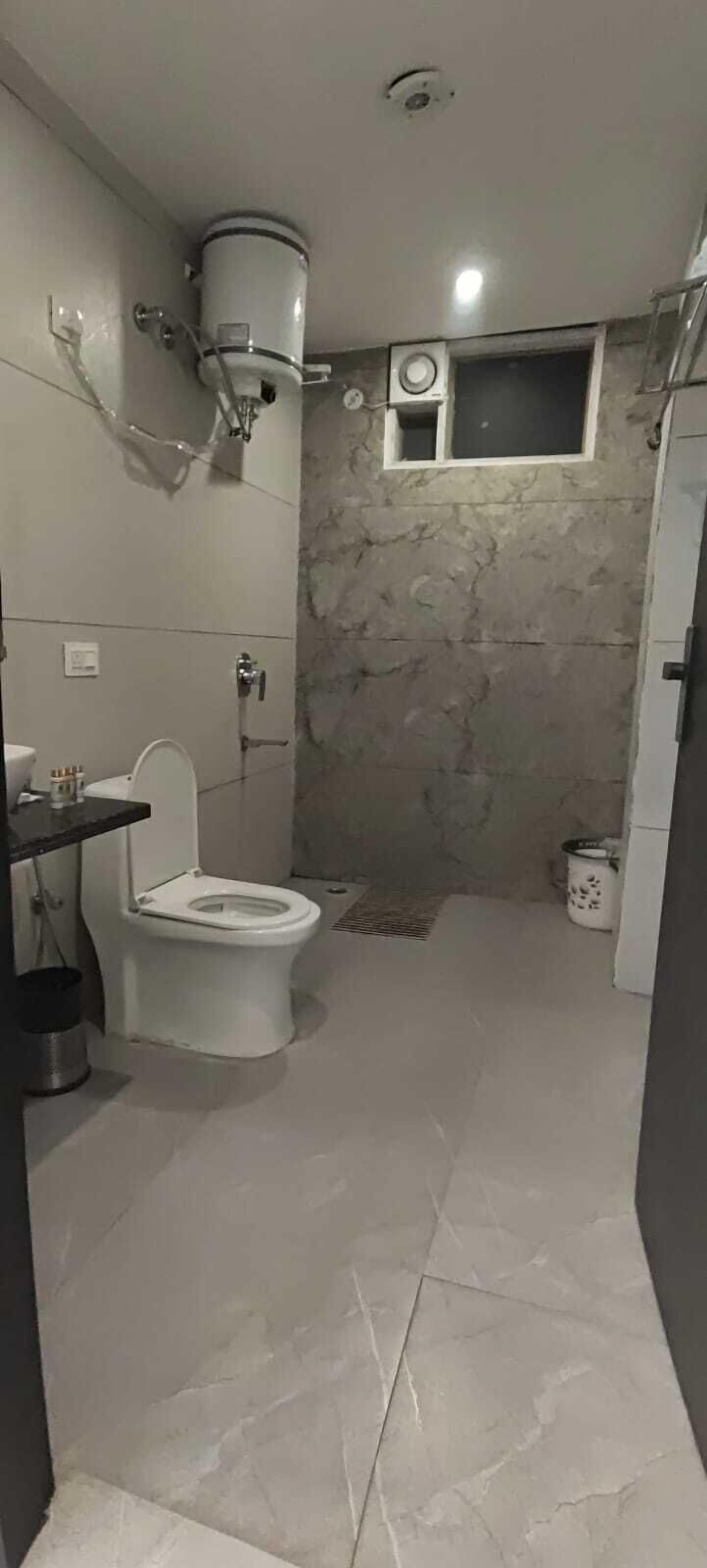 A bathroom with a toilet, a shower, a sink, and a window.