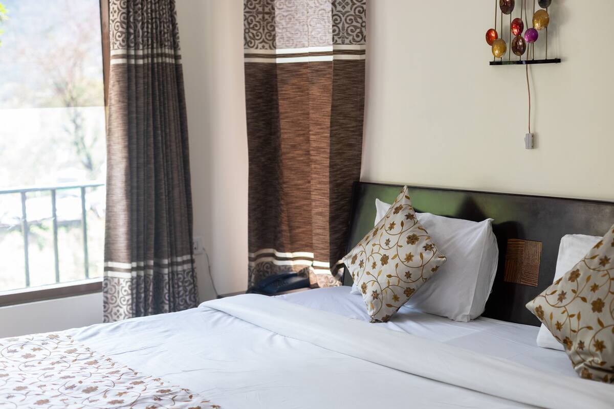 A neatly made bed with patterned pillows, a headboard with a textured panel, and a wall-mounted light fixture.