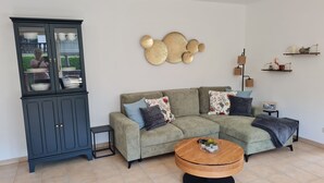 A living room with a sectional sofa, a wooden coffee table, a cabinet with glass doors, and wall decor. - Central in August 2022 newly renovated apartment Katja II with Kramerblick (Garmisch-Partenkirchen)