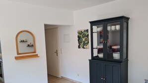 A hallway with a dark wooden cabinet containing dishes, a mirror with a wooden frame, and a door leading to another room. - Central in August 2022 newly renovated apartment Katja II with Kramerblick (Garmisch-Partenkirchen)