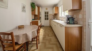 A compact kitchen with a dining table, chairs, and a small island with a coffee machine. - Pleasant house with garden - Near downtown (Albi)