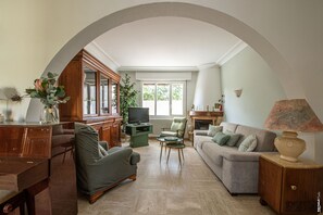 Uma sala de estar com televisão, sofá, poltrona e mesa de centro.
