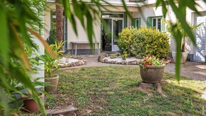 A courtyard with a building entrance, potted plants, and a small seating area. - Pleasant house with garden - Near downtown (Albi)