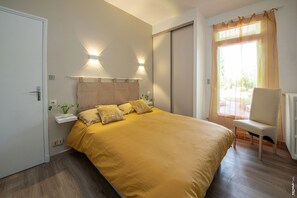 Quarto com uma cama grande, luminárias laterais, uma cadeira e janela com cortinas.