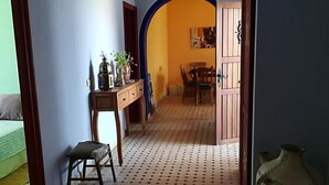 A room with a patterned floor, a wooden desk, a chair, a table, and a dining area visible through an archway. - DAR CLARA, or DAR FKRUN (Double room) (Arcila-Mejlaw)