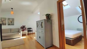 En hyggelig og kompakt stue med sofa, lille bord, skab og seng.