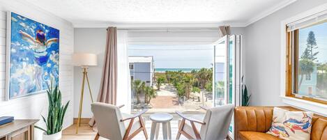 A modern living room with a sofa, chairs, a coffee table, and a view of the ocean.