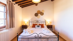 A neatly made bed with white linens and rolled towels, two bedside lamps, a wooden ceiling, and a window with curtains. - Leondardo Apartment ~ LE FRAINE (New Opening 2022) (Santa Luce)