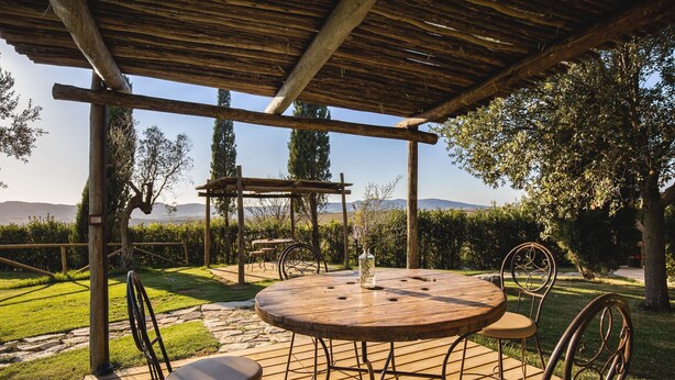 A wooden pergola with a round table and chairs in a garden setting. - Leondardo Apartment ~ LE FRAINE (New Opening 2022) (Santa Luce)