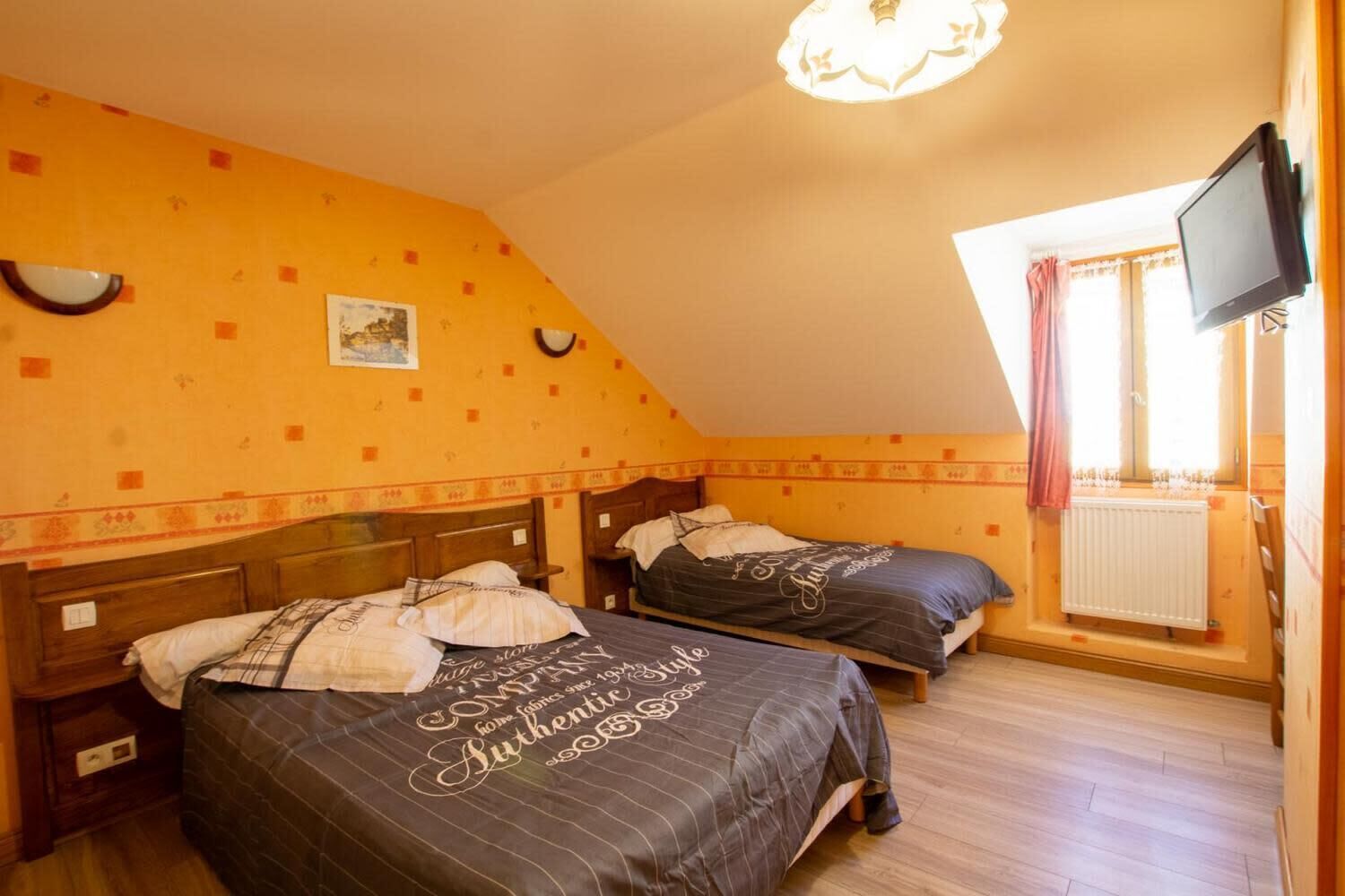 A bedroom with two beds, a television, and a window with curtains.