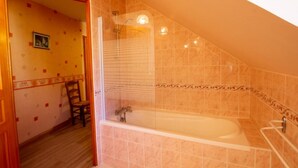 Une salle de bain avec une baignoire, une douche et une chaise en bois.