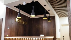 A reception desk with a wooden finish and a sign that reads "ROOTTOP." There are three pendant lights above the desk. - Rooftop Apart Hotel (Yerevan)