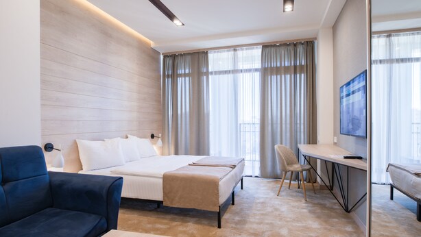 A modern hotel room with a bed, a desk, a chair, and a TV. - Rooftop Apart Hotel (Yerevan)