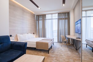 Una habitación de hotel moderna con una cama, un escritorio, una silla y un televisor.