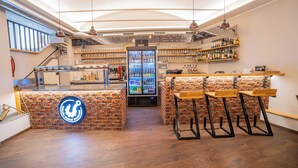 A bar area with a brick counter, stools, and a refrigerator stocked with beverages. - LUMA TERRA PRAGUE (Prague)