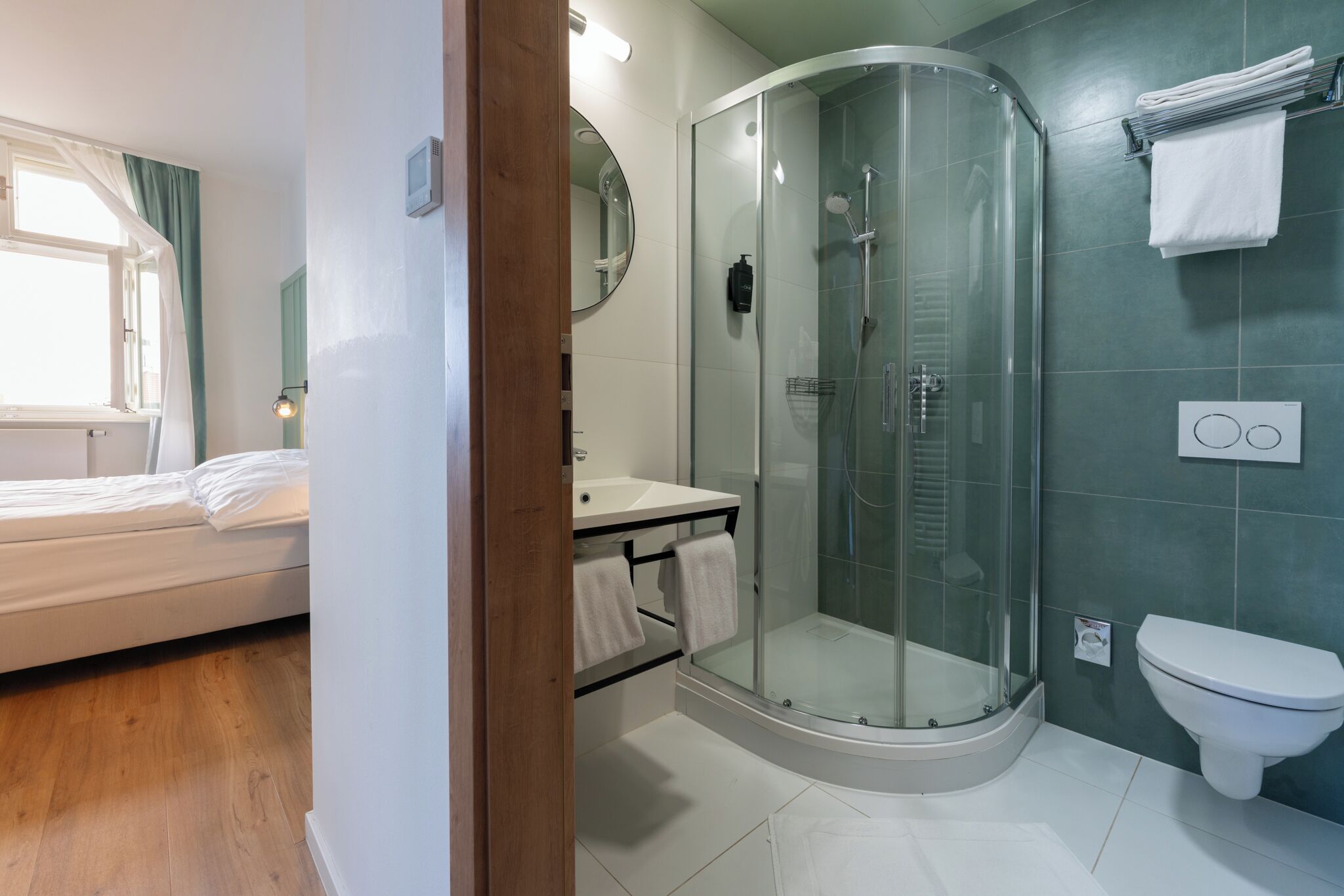A modern bathroom with a glass-enclosed shower, a white toilet, and a sink with a mirror.