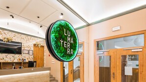 A modern hotel lobby with a reception desk, a large circular sign, and a staircase. - LUMA TERRA PRAGUE (Prague)