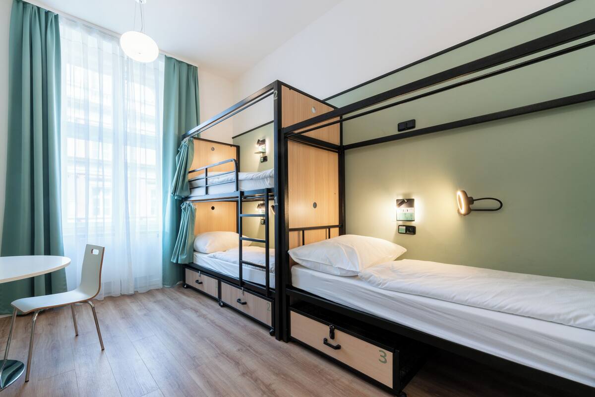 A dormitory room with bunk beds, a desk, and a chair.
