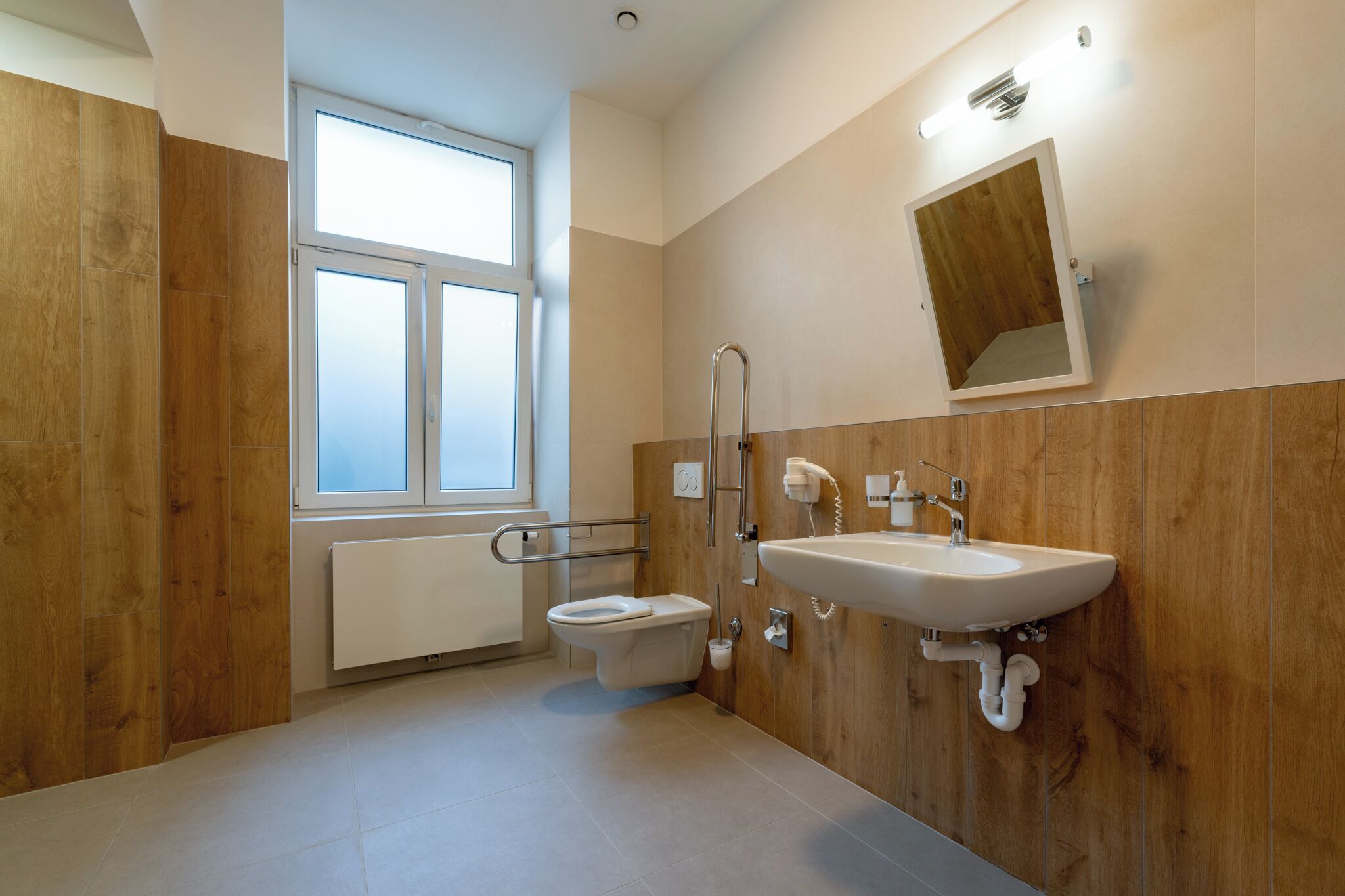 A modern bathroom with a toilet, sink, and wooden paneling.