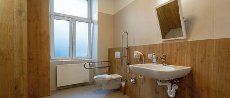 A modern bathroom with a toilet, sink, and wooden paneling.