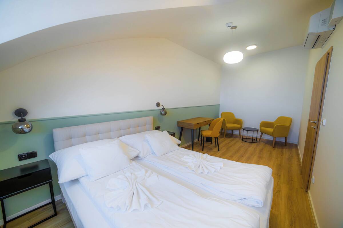 A hotel room with a bed, a desk, two chairs, and a small table.
